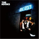 The Kooksin "Konk"-albumin kansikuva. Siinä näkyy mustaa taustaa vasten oikealla neonsinisellä värillä liikemerkki oven suuaukon yläpuolella. Oviaukossa lauma miehiä. Vasemmassa yläkulmassa bändin logo valkoisella värillä.