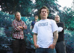 Markus Henttosen ottama bändikuva Dark Filth Fraternitysta. Kuvassa näkyy neljä miestä, jotka seisovat ulkoilmassa pöpelikön edustalla. Etualalla valkoiseen t-paitaan ja sinisiin farkkuihin pukeutunut meis, jonka takana kolme muuta heppua seisovat.