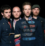 Coldplay-bändin nelihenkinen miehistö seisoo mustaa taustaa vasten rivissä. Kuvassa keskimmäisenä seisovalla miehellä omituinen ta kki, jossa vihreitä, sinisiä ja punaisia raitoja. Oikeassa laidassa näkyvän miehen päässä vihertävä lippis.