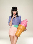 Valokuva Katy Perry -nimisestä amerikkalaisesta laulajattaresta. Naisella mustat hiukset, lyhyt pinkki hame ja violetti paita. Toisessa kädessä hänellä suuri jäätelötötterö. Tausta on luonnonvalkoinen.
