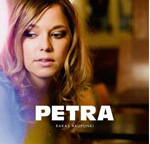 Petran albumin "Rakas kaupunki" etukannessa nainen, jolla katse luotu alaspäin. Kuvan alaosassa valkoisella värillä lukee pelkistetyin kirjaimin Petra ja sen alla hyvin pienellä tekstillä albumin nimi.