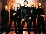 Kuusipäinen Iron Maiden -bändi seisoo punertavaa taustaa vasten pukeutuneina mustiin vaatteisiin. Miehet seisovat rivissä. Etummaisena ja keskmmäisenä lyhyeen mustaan nahkatakkiin pukeutunut lyhythiuksinen mies.