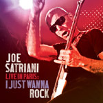 Valokuva kitaraa soittavasta Joe Satrianista. Miehellä mustat aurinkolasit silmillä ja pää ilman hiuksia. Miehellä musta t-paita. Kuvan värimaailma on punertava ja kirkas spottivalo hohtaa ylhäällä. Vasemmassa alakulmassa lukee tikkukirjaimin valkoisella,