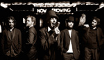 Progerockia soittavan Karnivool-bändin jäsenet seisovat rivissä harmaasävyisessä valokuvassa. Kuvassa näkyy viisi mustiin pukuihin pukeutunutta miestä, joista keskimmäinen seisoo etualalla ja laulaa hattu päässä mikrofoniin. Kuvan taustalla yläosassa valk