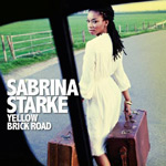 Sabrina Starken albumin "Yellow Brick Road" etukannessa näkyy valkoiseen leninkiin pukeutunut tummaihoinen nainen, jolla mustat hiukset ja käsissä kapsäkit. Kuvassa taustalla vihreää nurmikkoa ja tummaa pikitietä.